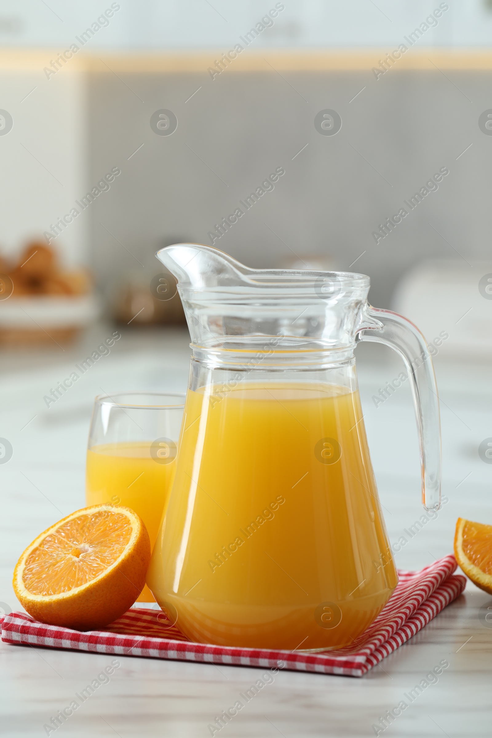 Photo of Tasty orange juice in jug, glass and citrus fruit on white marble table