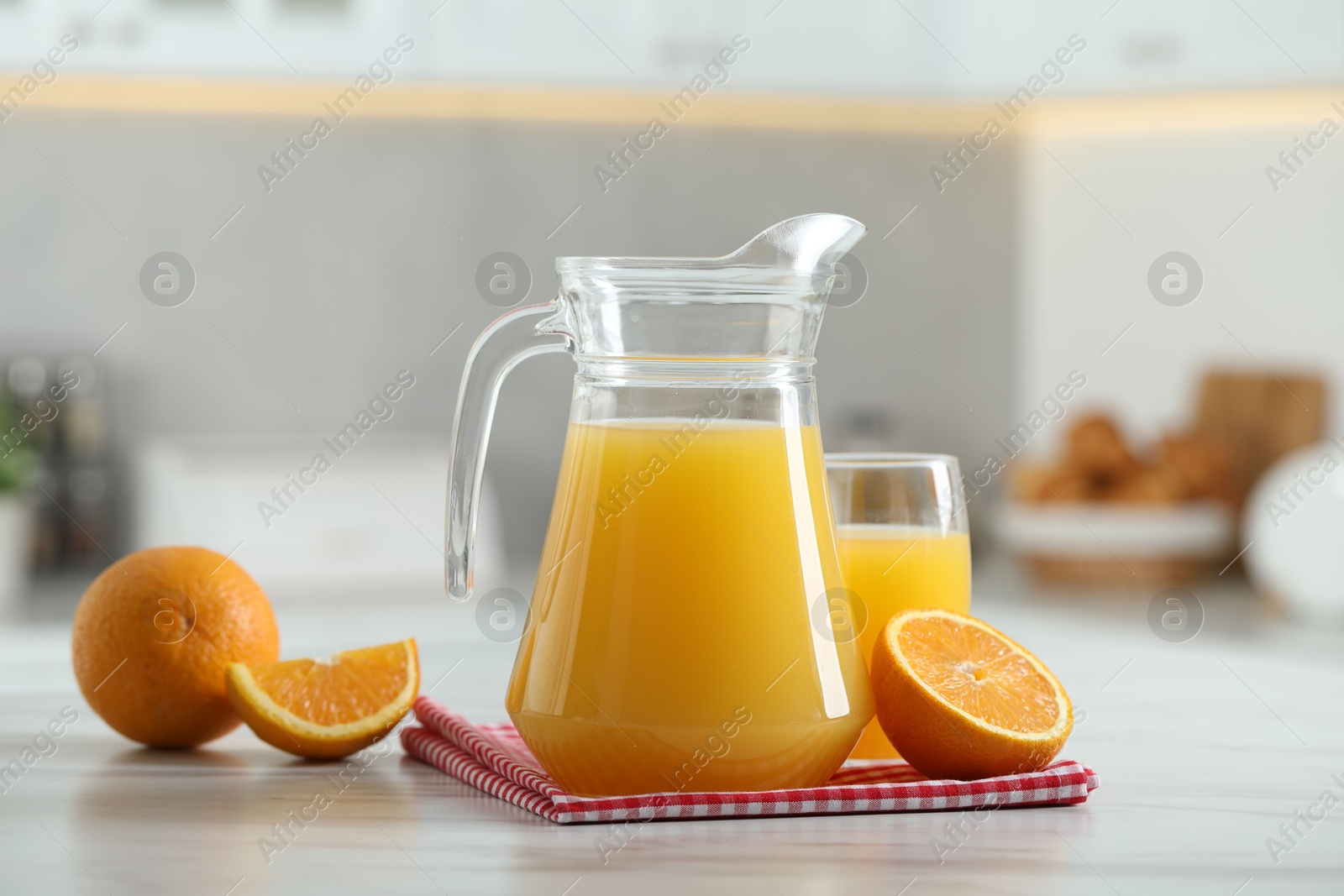 Photo of Tasty orange juice in jug, glass and citrus fruits on white marble table