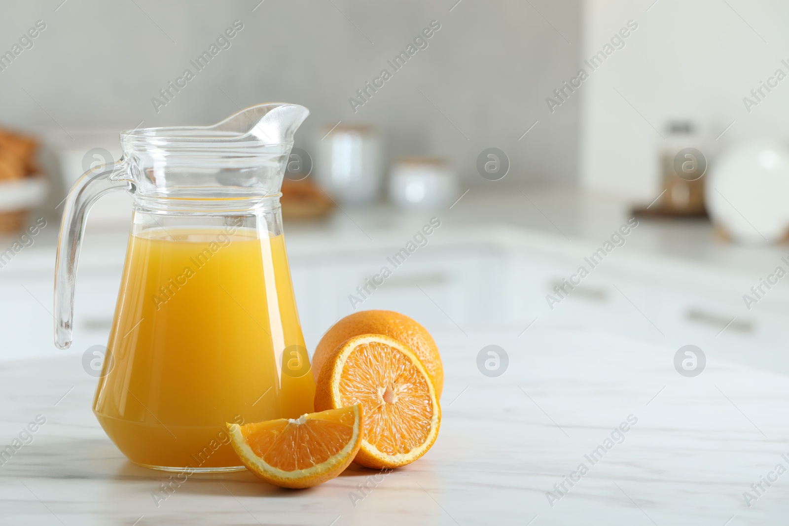 Photo of Tasty orange juice in jug and citrus fruits on white marble table. Space for text