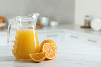 Tasty orange juice in jug and citrus fruits on white marble table. Space for text