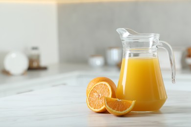 Photo of Tasty orange juice in jug and citrus fruits on white marble table. Space for text