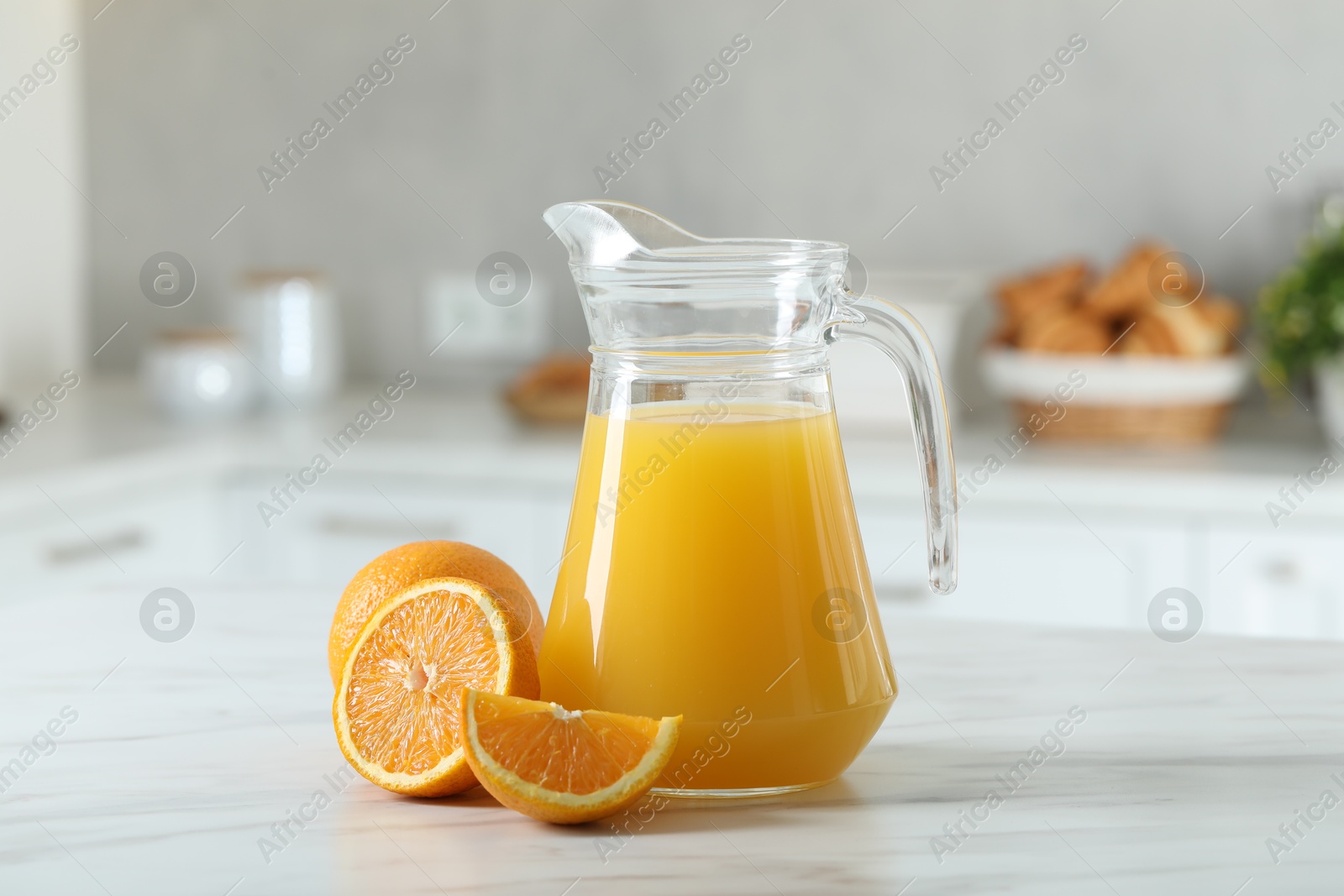 Photo of Tasty orange juice in jug and citrus fruits on white marble table