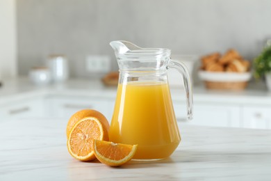 Tasty orange juice in jug and citrus fruits on white marble table