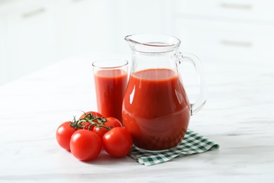 Tasty tomato juice in jug, glass and vegetables on white marble table