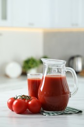 Photo of Tasty tomato juice in jug, glass and vegetables on white marble table