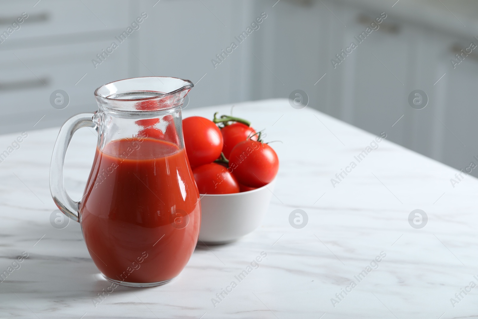 Photo of Tasty tomato juice in jug and vegetables on white marble table. Space for text