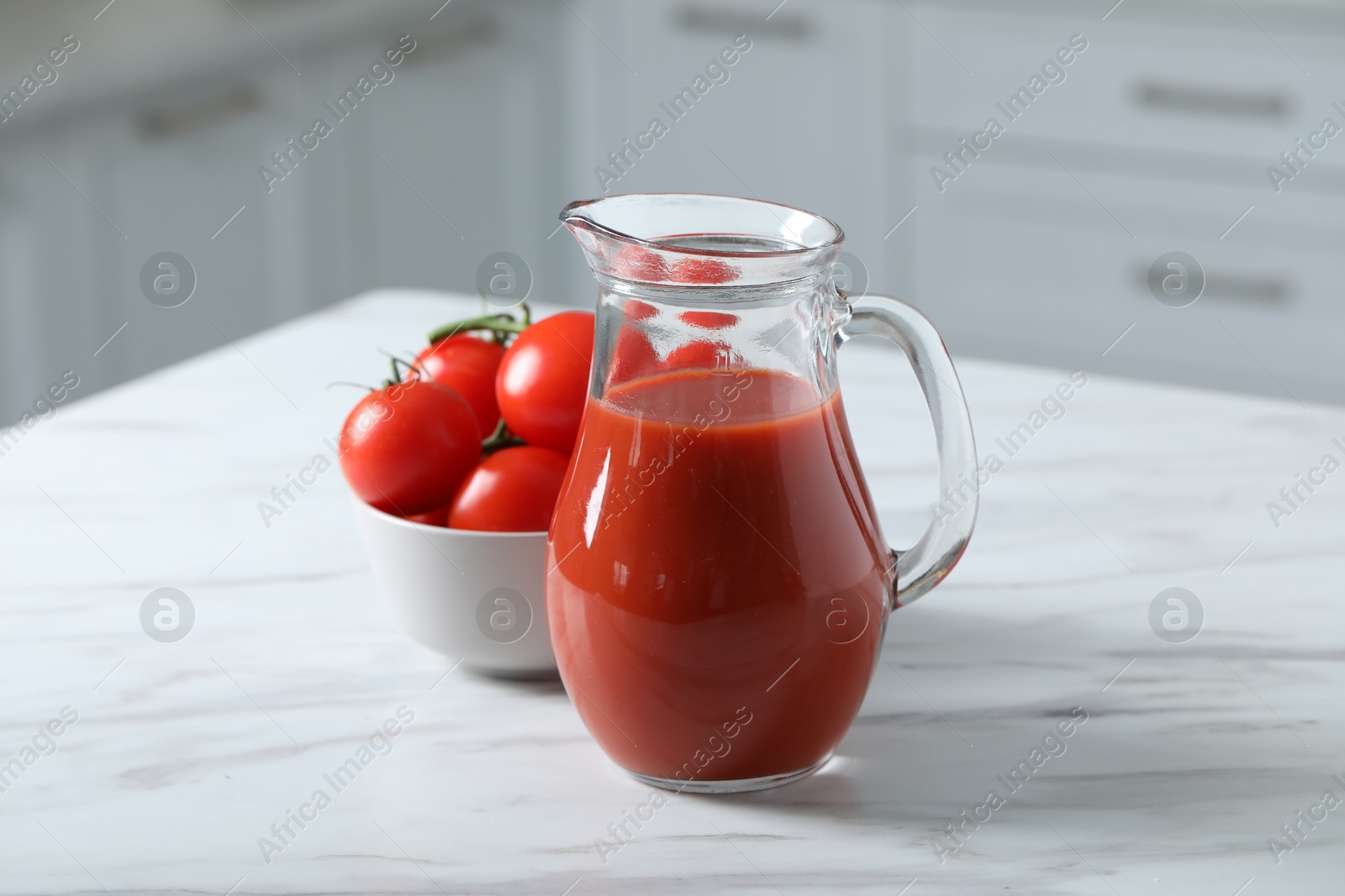 Photo of Tasty tomato juice in jug and vegetables on white marble table