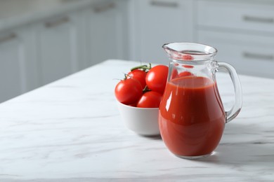 Photo of Tasty tomato juice in jug and vegetables on white marble table. Space for text