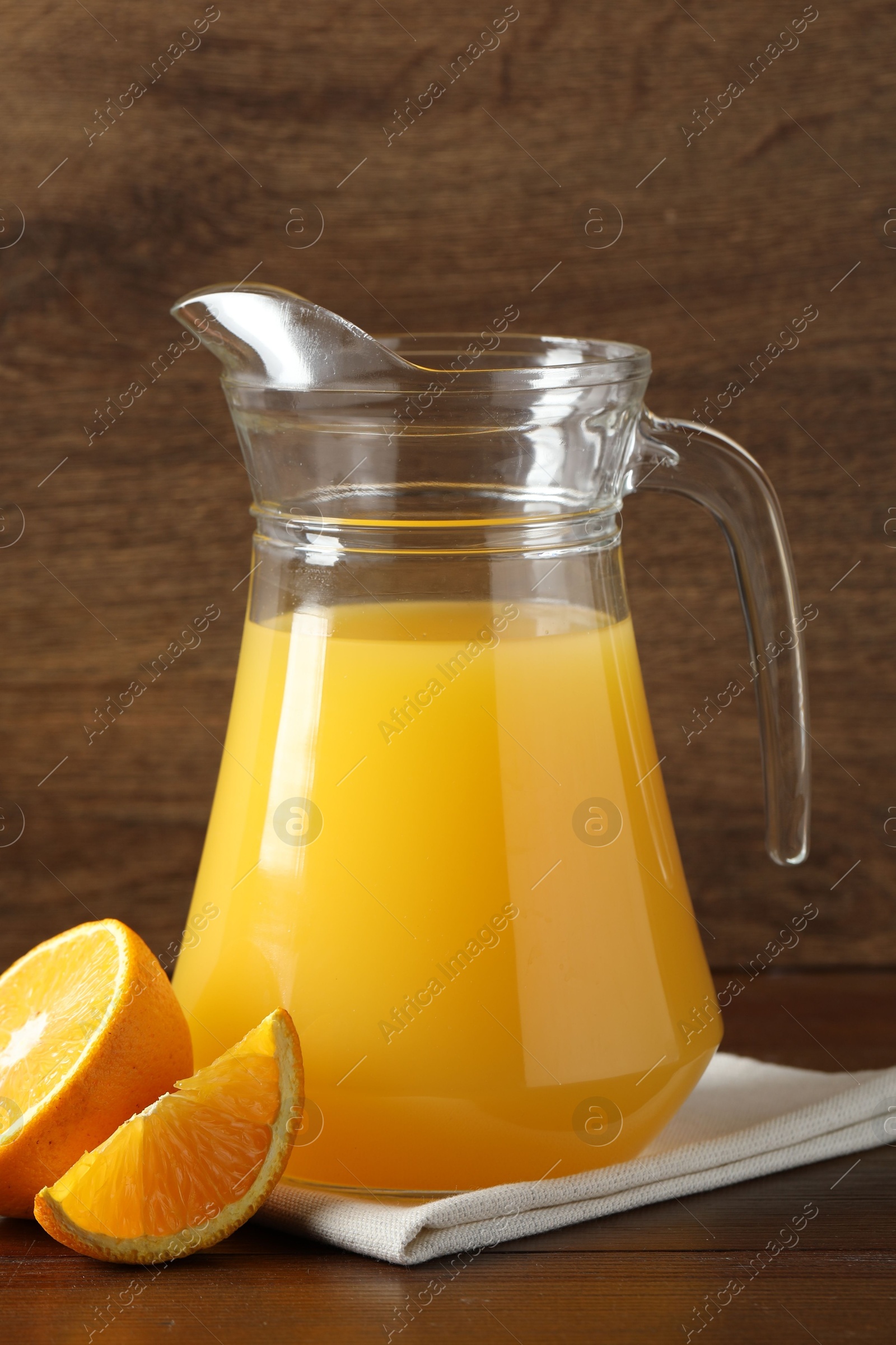 Photo of Tasty orange juice in jug and citrus fruit on wooden table