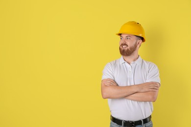 Photo of Engineer in hard hat on yellow background, space for text