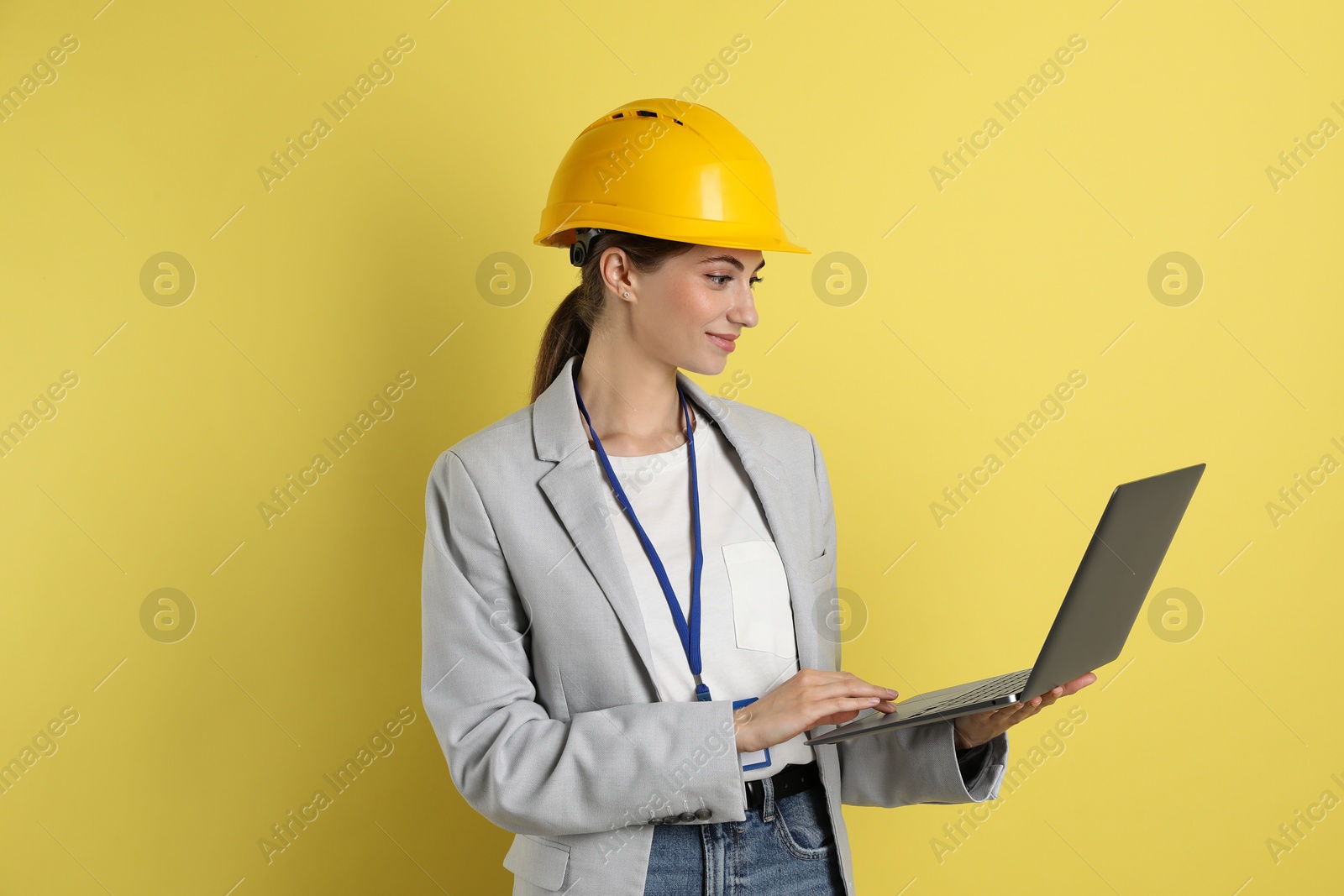 Photo of Engineer in hard hat with laptop on yellow background