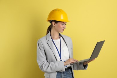 Photo of Engineer in hard hat with laptop on yellow background