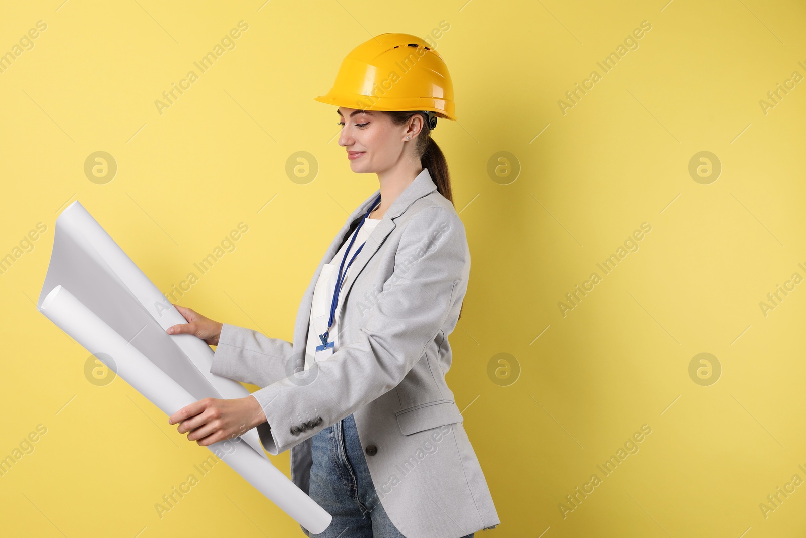 Photo of Engineer in hard hat with draft on yellow background, space for text