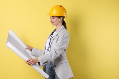 Engineer in hard hat with draft on yellow background, space for text