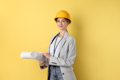 Engineer in hard hat with drafts on yellow background