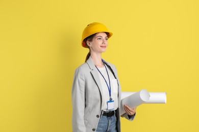 Photo of Engineer in hard hat with drafts on yellow background