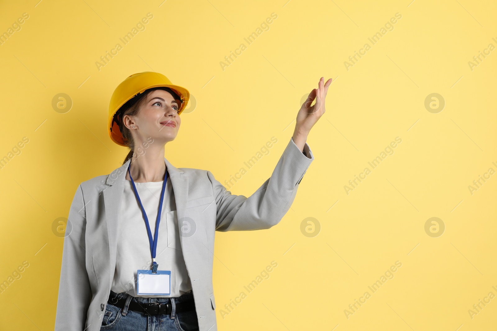 Photo of Engineer in hard hat on yellow background, space for text