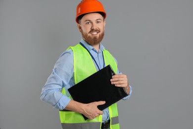 Photo of Engineer in hard hat with clipboard on grey background