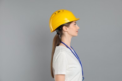 Engineer in hard hat on grey background, space for text