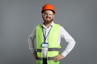 Engineer in hard hat and goggles on grey background