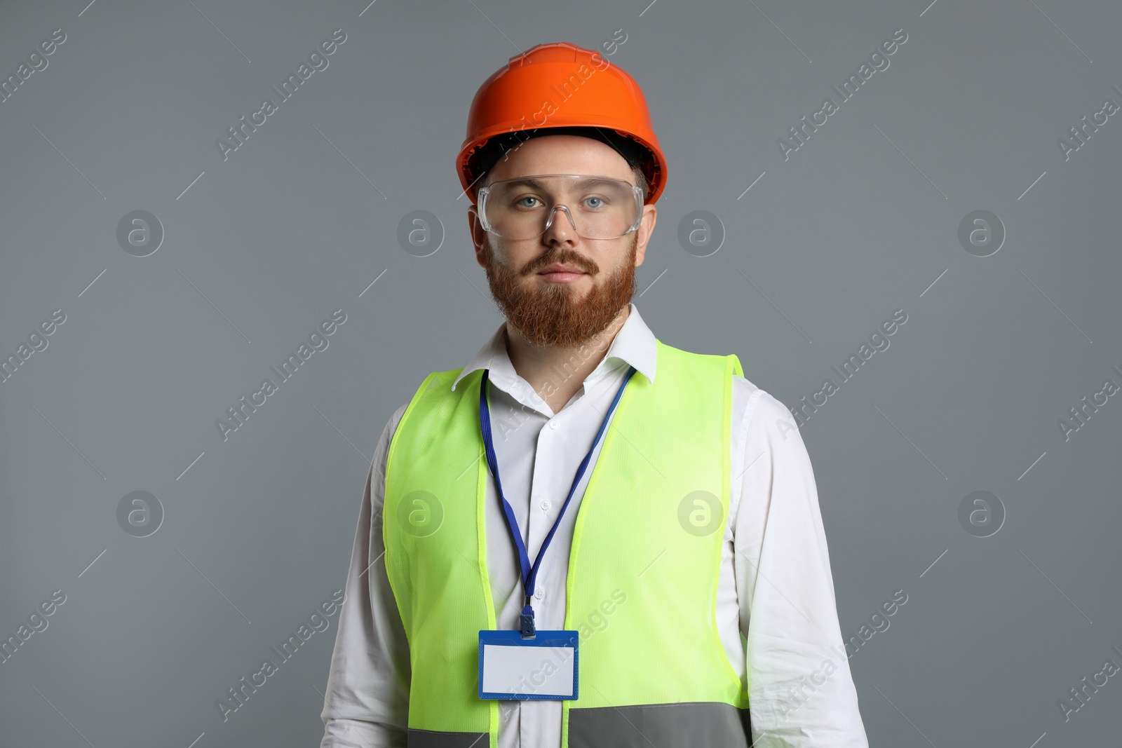 Photo of Engineer in hard hat and goggles on grey background