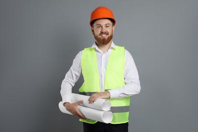 Photo of Engineer in hard hat with drafts on grey background