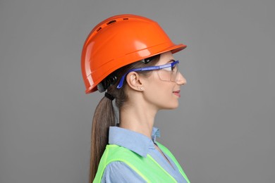 Photo of Engineer in hard hat and goggles on grey background