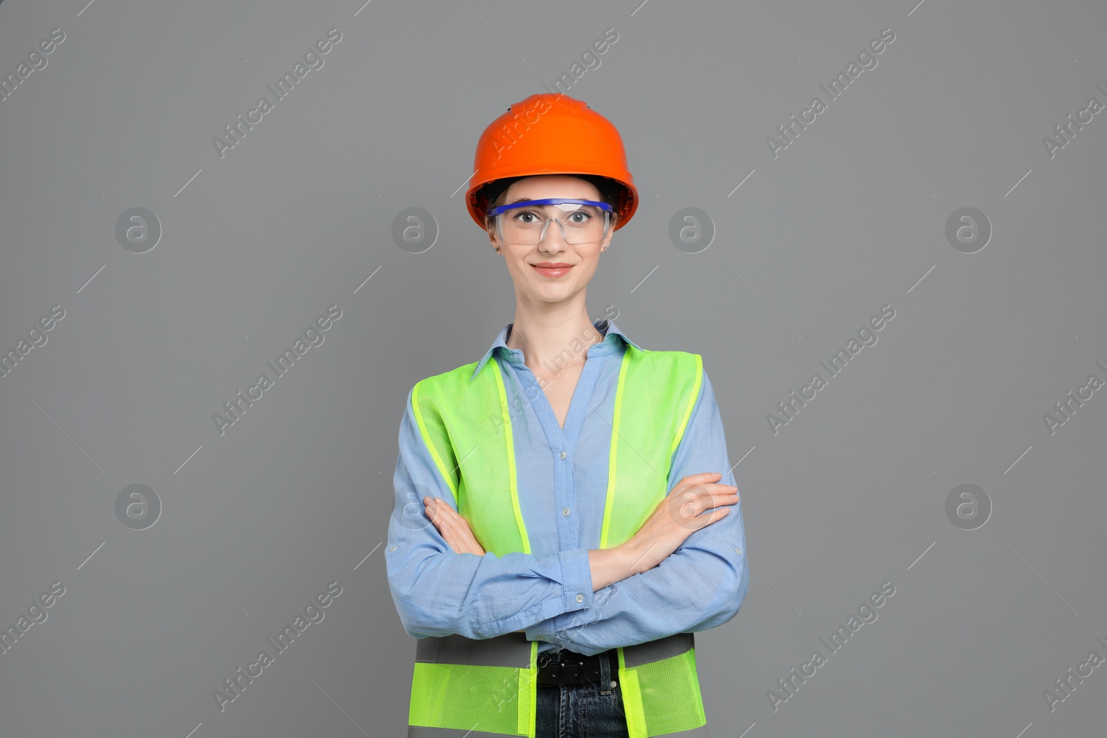 Photo of Engineer in hard hat and goggles on grey background