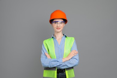 Photo of Engineer in hard hat and goggles on grey background