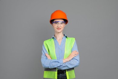 Engineer in hard hat and goggles on grey background