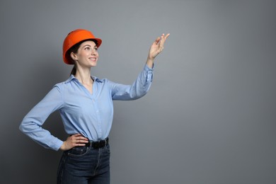 Engineer in hard hat on grey background, space for text