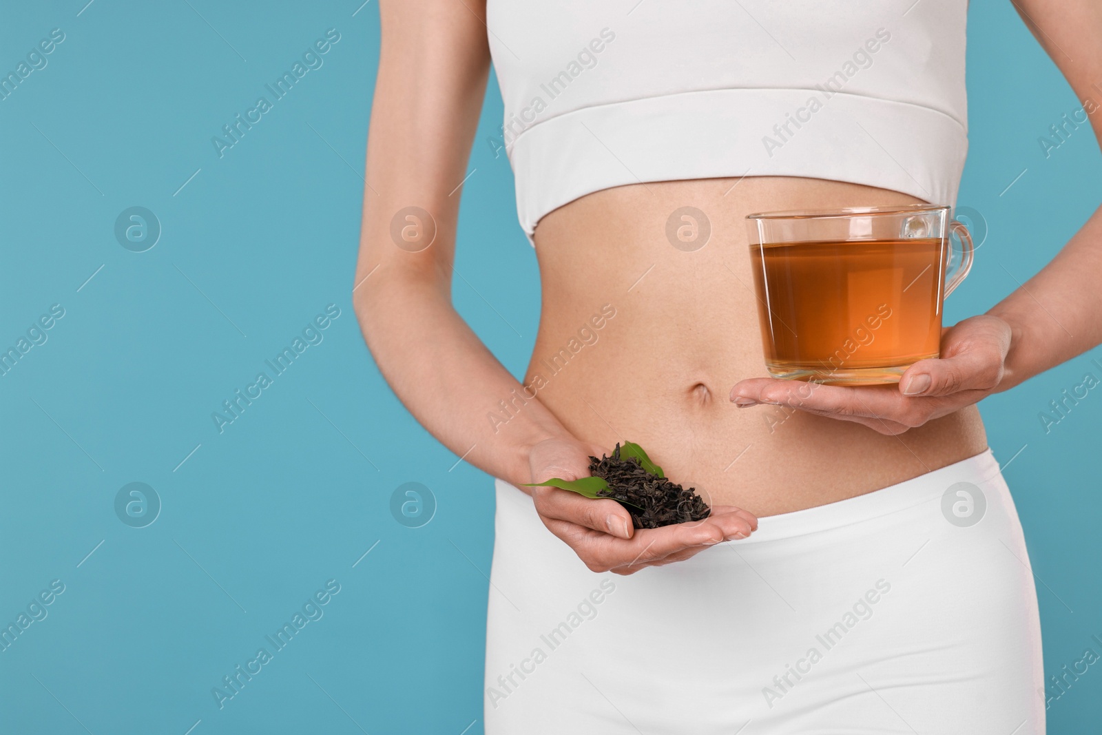 Photo of Weight loss concept. Woman with cup of diet tea and dry leaves on light blue background, closeup