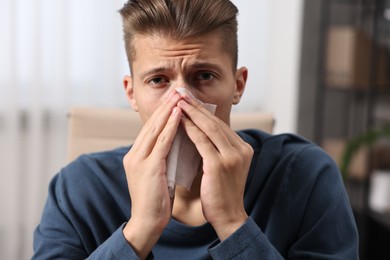 Photo of Young man with tissue suffering from sinusitis indoors