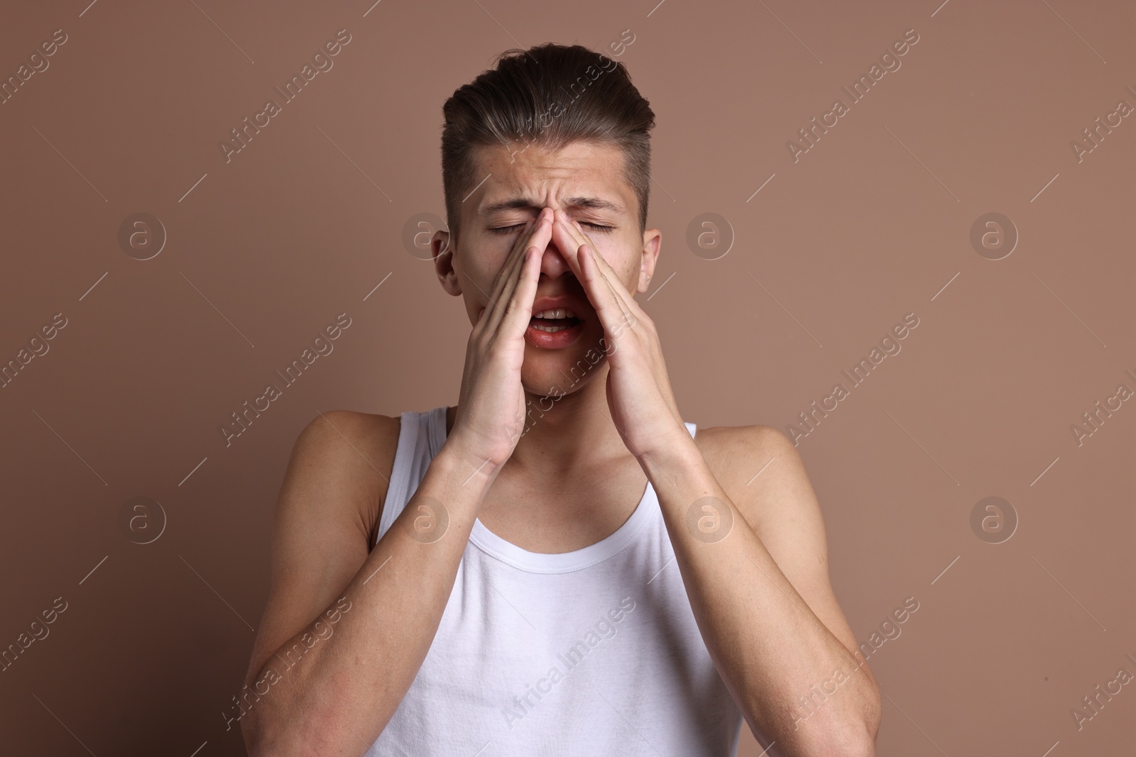 Photo of Young man suffering from sinusitis on light brown background