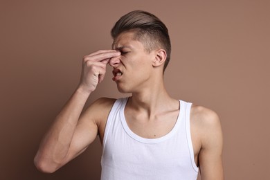 Photo of Young man suffering from sinusitis on light brown background