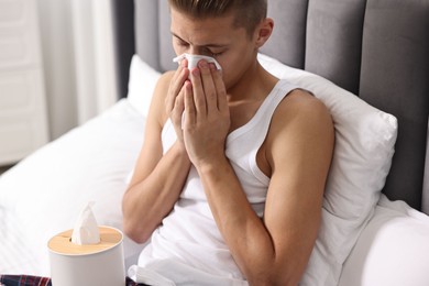 Young man with tissue suffering from sinusitis in bed at home