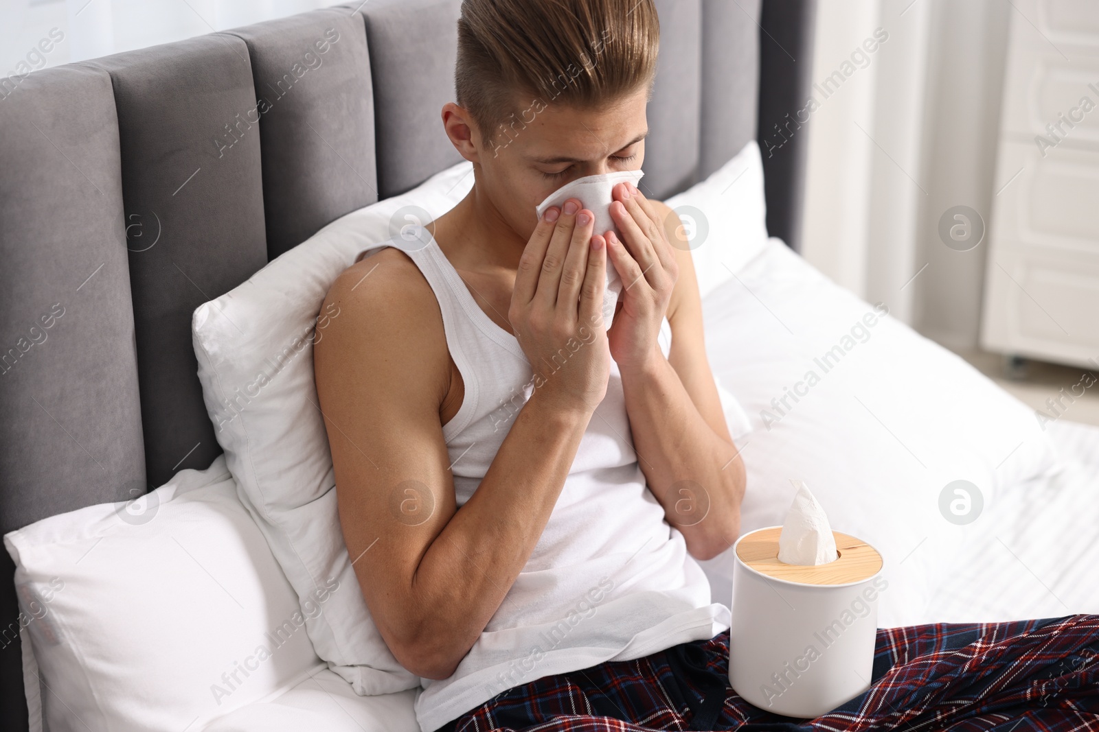 Photo of Young man with tissue suffering from sinusitis in bed at home