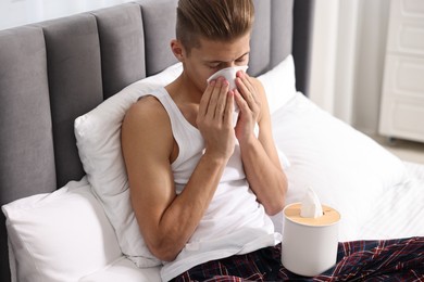 Young man with tissue suffering from sinusitis in bed at home