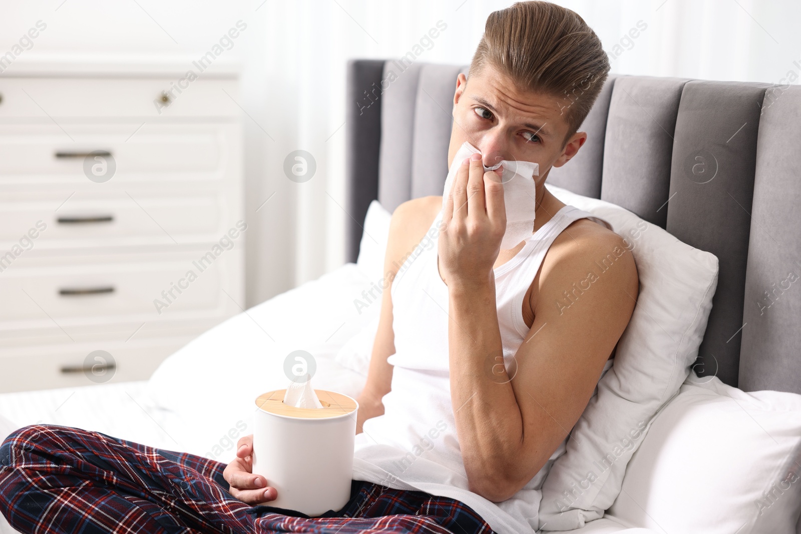 Photo of Young man with tissue suffering from sinusitis in bed at home