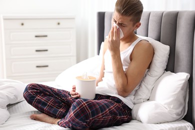 Young man with tissue suffering from sinusitis in bed at home