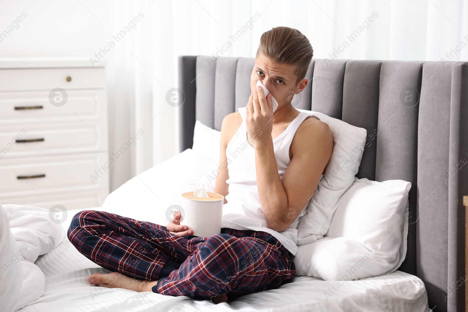 Photo of Young man with tissue suffering from sinusitis in bed at home