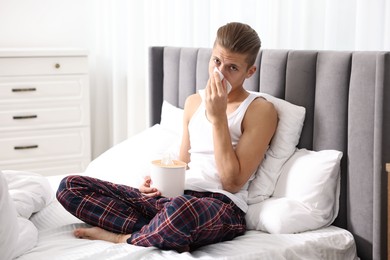 Young man with tissue suffering from sinusitis in bed at home