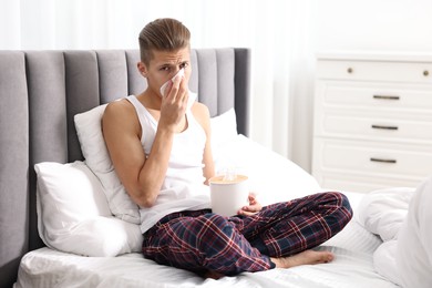 Photo of Young man with tissue suffering from sinusitis in bed at home