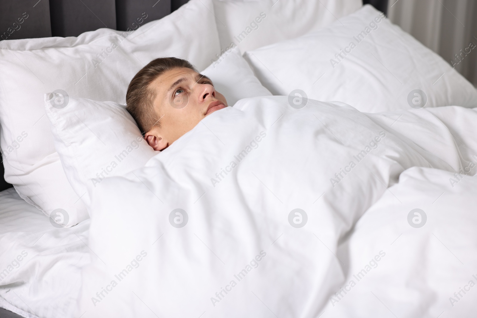 Photo of Young man suffering from sinusitis and lying in bed at home