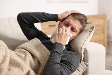 Young man with tissue suffering from sinusitis and lying in bed at home