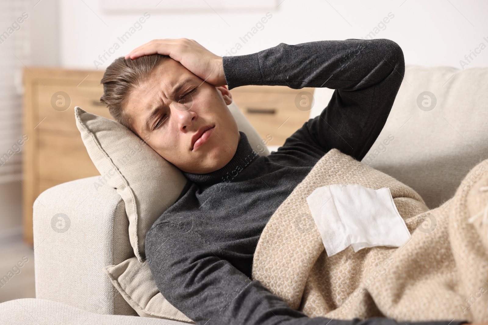 Photo of Young man with tissue suffering from sinusitis and lying in bed at home