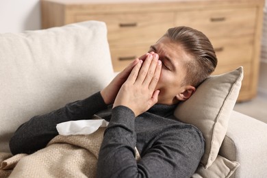 Photo of Young man suffering from sinusitis and lying in bed at home