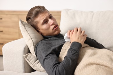 Young man with tissue suffering from sinusitis and lying in bed at home