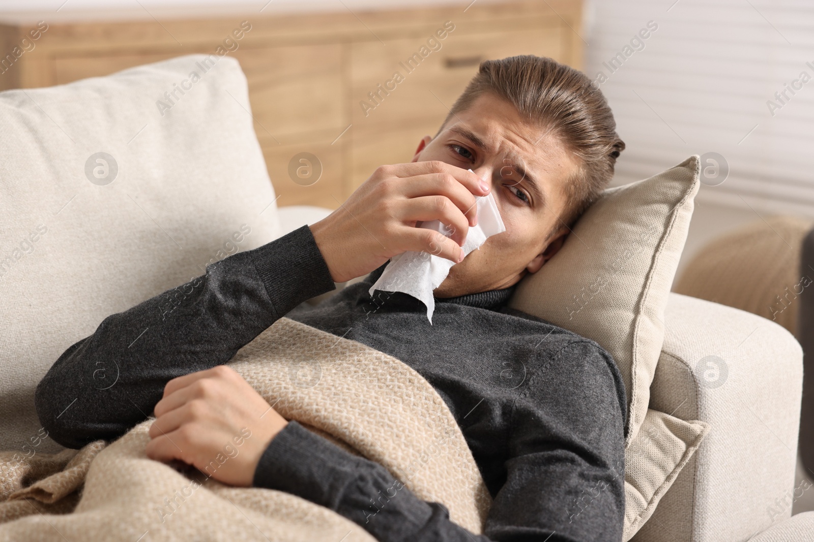 Photo of Young man with tissue suffering from sinusitis and lying in bed at home