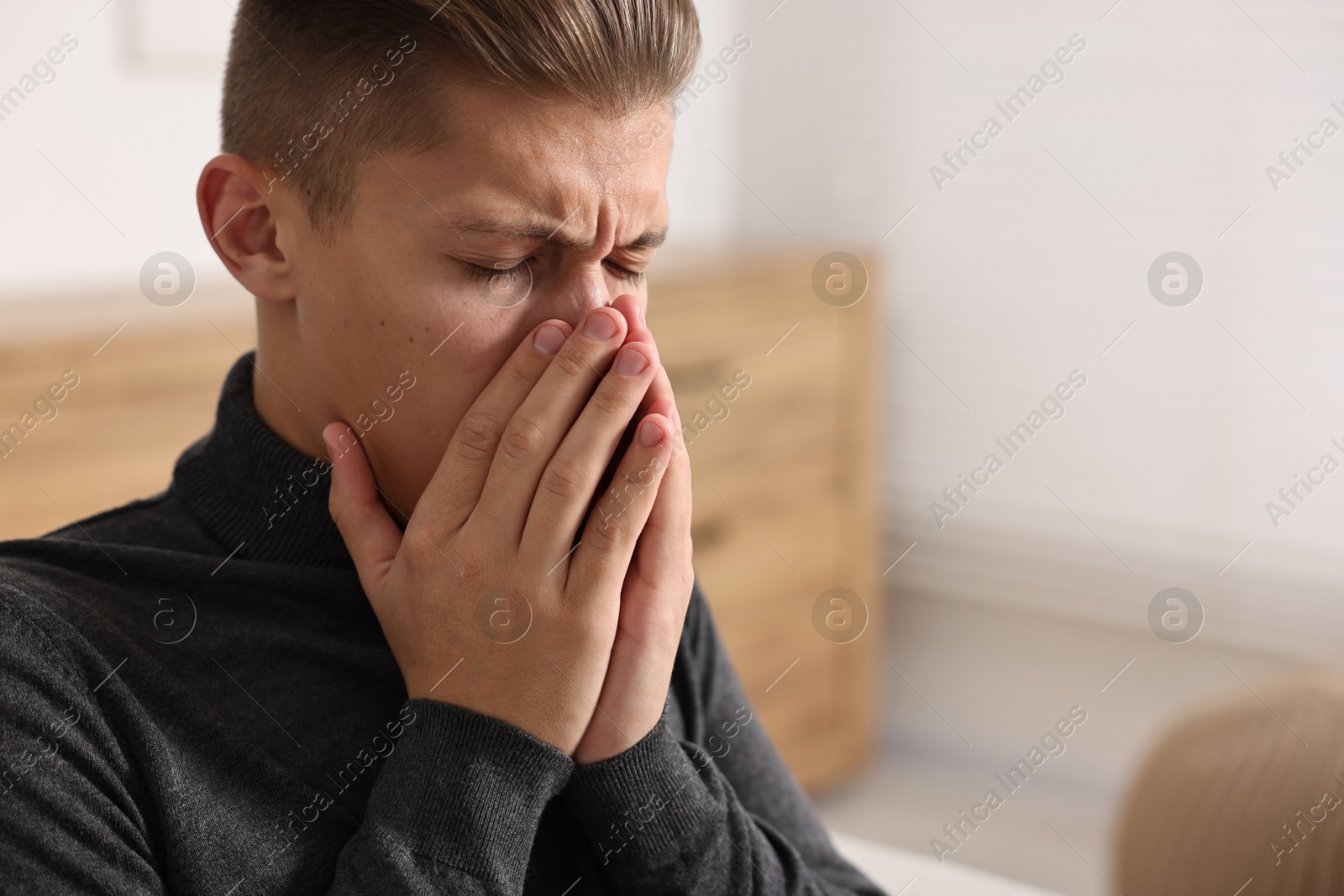 Photo of Young man suffering from sinusitis at home, space for text